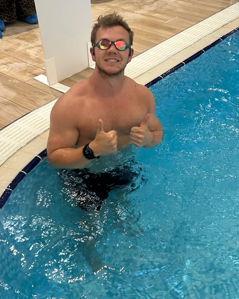 Lance in a swimming pool giving a thumbs up before a long swim